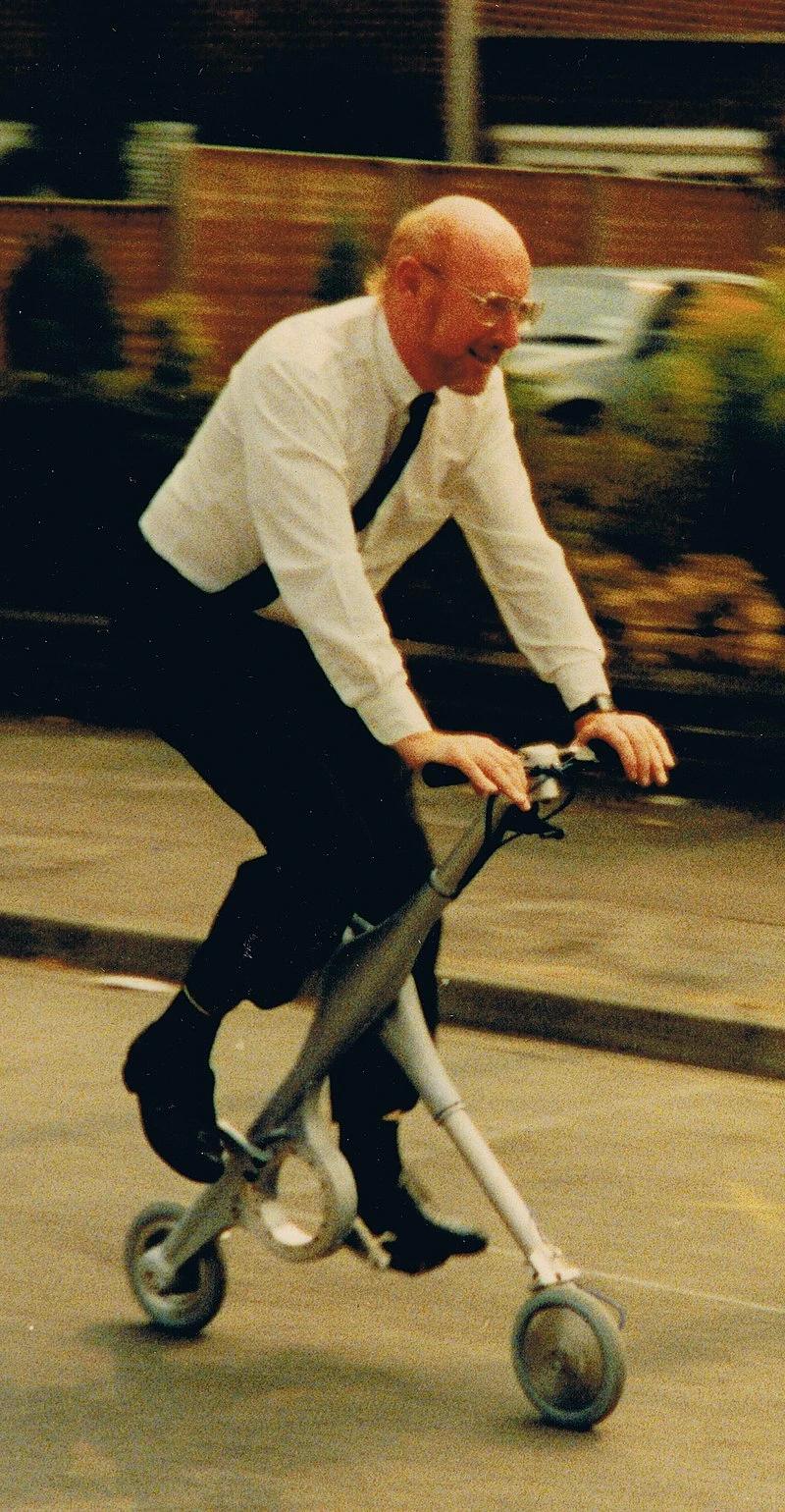 Clive Sinclair riding a compact three-wheeled folding bicycle