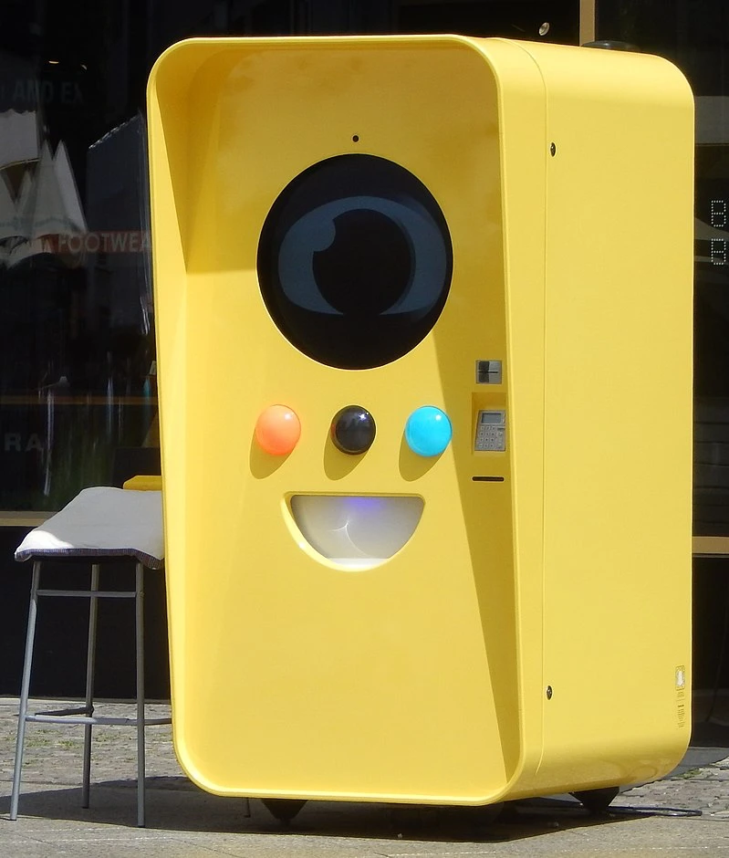 Bright yellow Snapbot vending machine with a large camera-lens design and three colored buttons