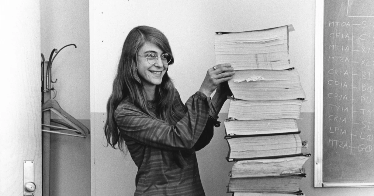 Margaret Hamilton standing beside the stack of Apollo guidance software listings she and her team wrote, 1969